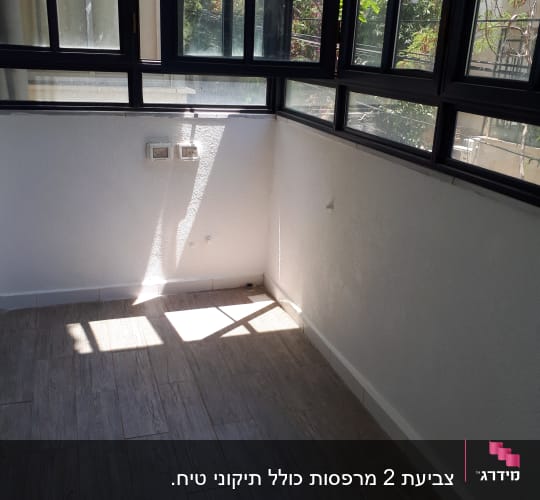 קיר לבן עם חלונות גדולים ואור שמש חודר